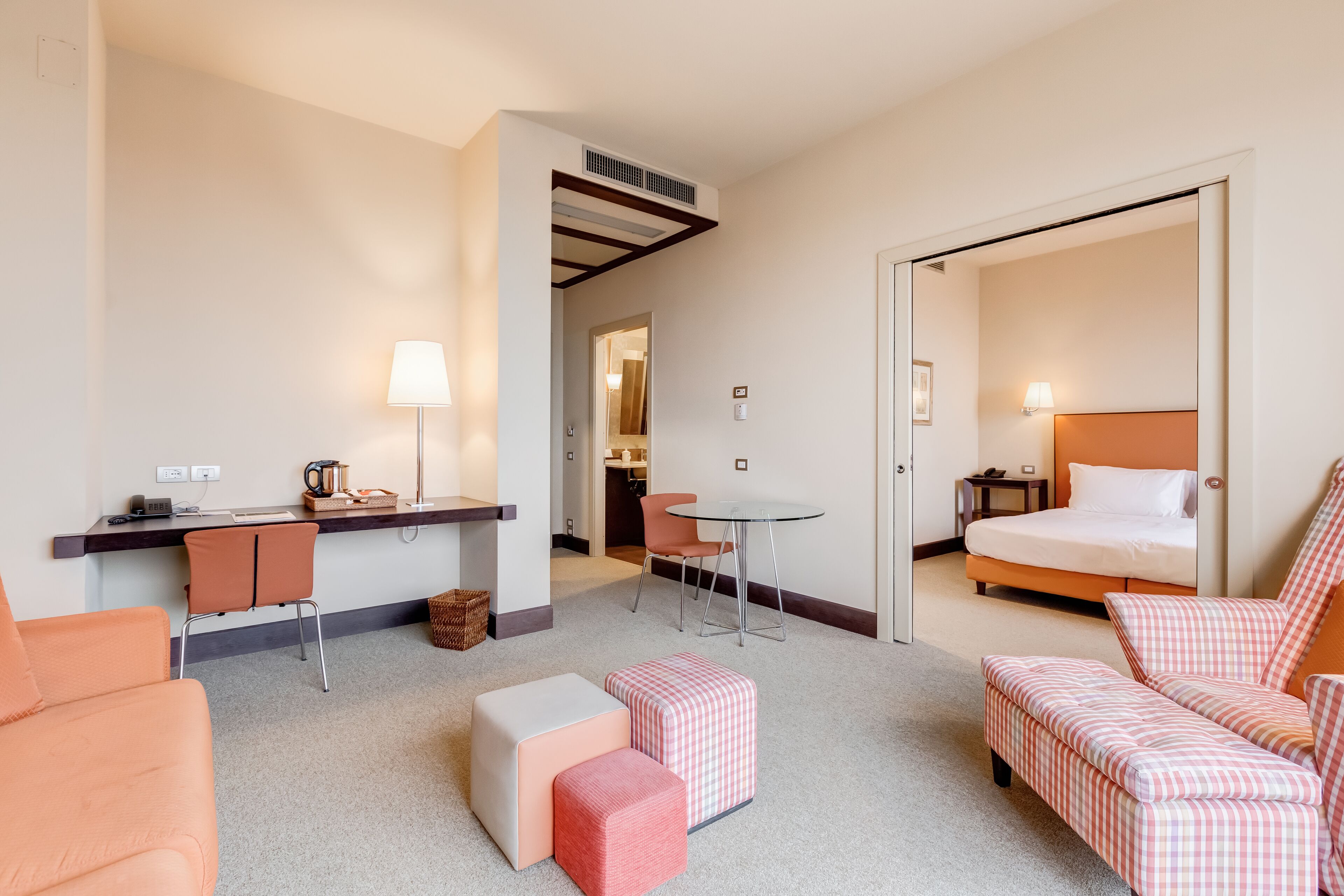 Ein Hotelzimmer mit einem Bett, einem Schreibtisch, einem Sessel, einem Tisch und Hocker.