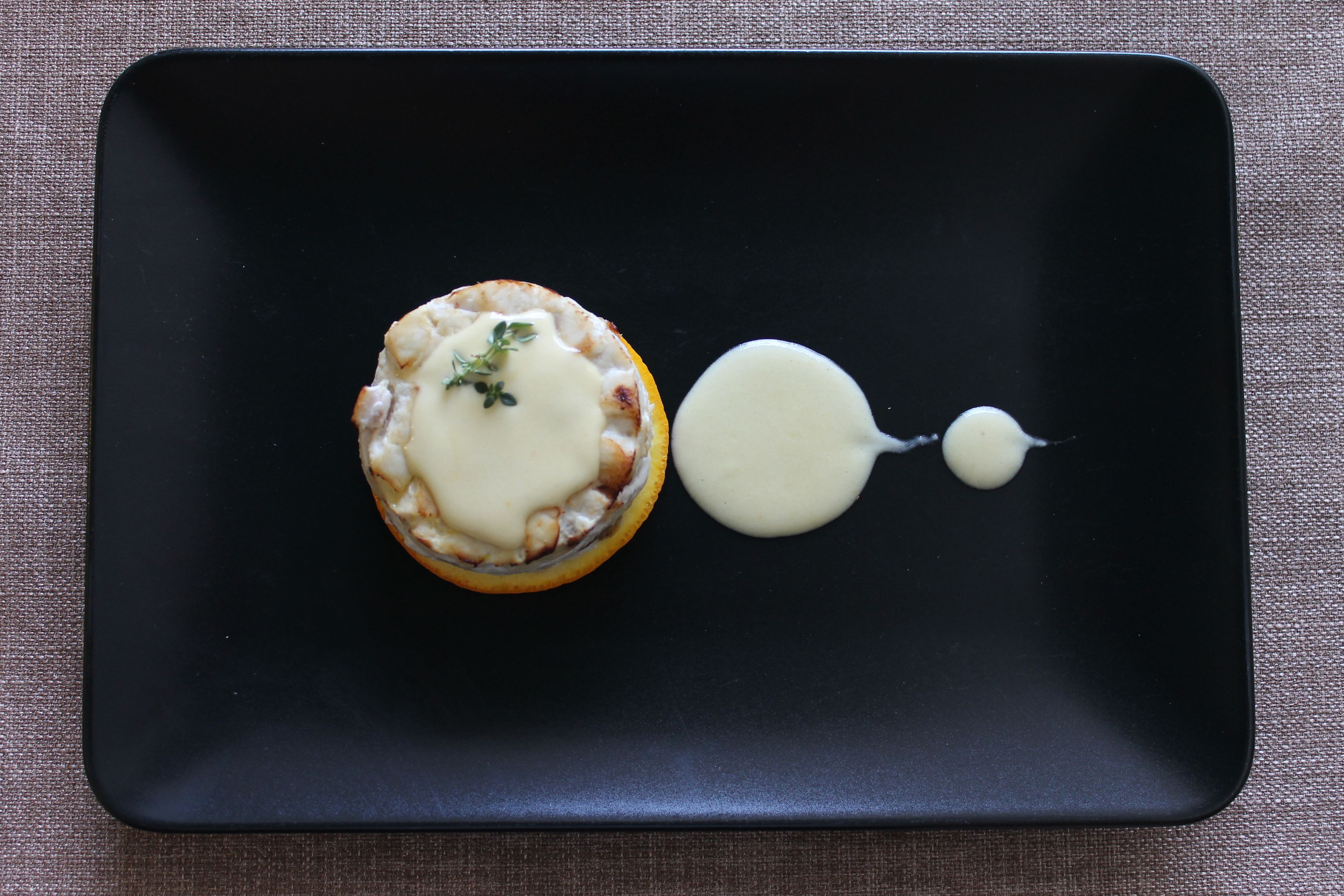 A black plate with a dessert and a dollop of sauce.