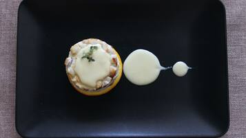 Un plato negro con un postre y una cucharada de salsa.