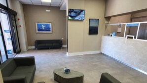A reception area with a reception desk, a black sofa, and a coffee table. - Hotel Il Gabbiano (Termini Imerese)