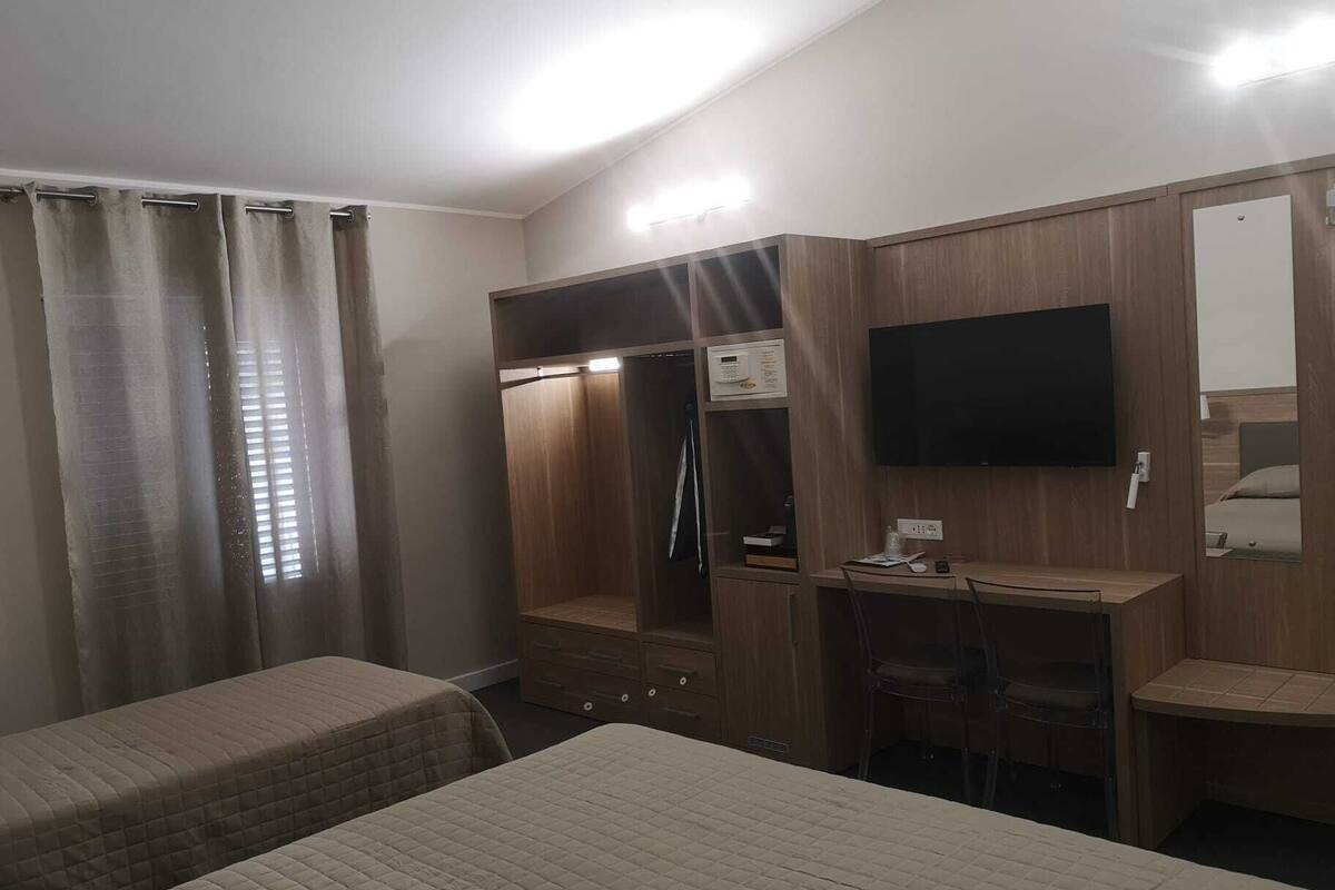A hotel room with a bed, a desk, a TV, and a wardrobe.