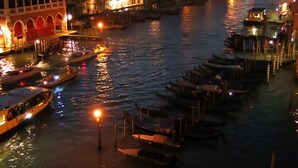 A nighttime view of a canal with boats docked along the sides, illuminated by street lamps and building lights. - Locanda Ai Santi Apostoli (Venice)