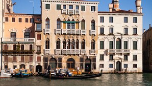 A canal with a gondola and boats, historic buildings with balconies, and a clear blue sky. - Locanda Ai Santi Apostoli (Venice)