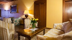 A cozy living room with striped sofas, a wooden coffee table, a vase with yellow flowers, and a lamp. - Locanda Ai Santi Apostoli (Venice)