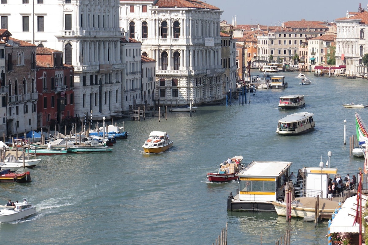 A canal with boats, historic buildings, and a clear sky.