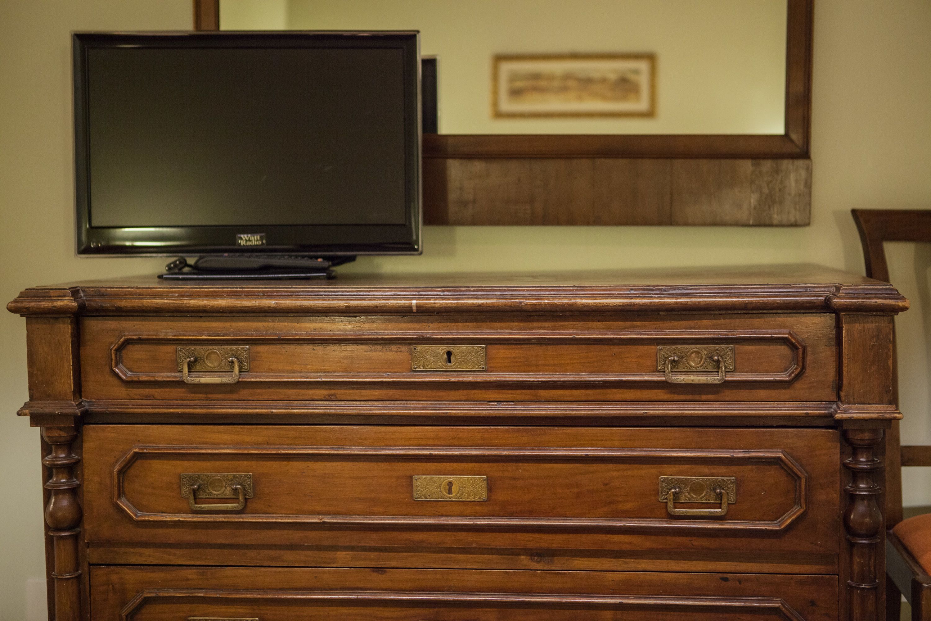 A wooden dresser with drawers and a television on top.