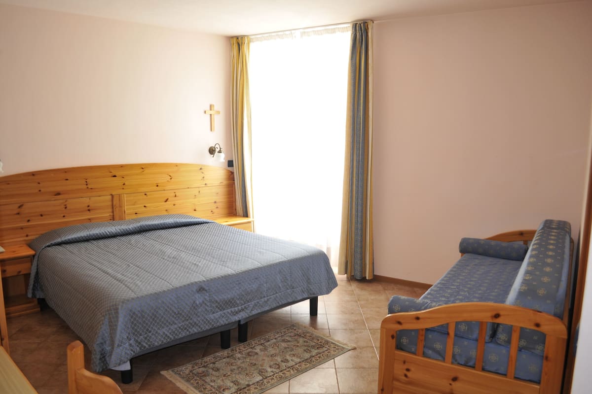 Una camera da letto con una testiera in legno, un letto con copriletto blu, una panca in legno e un piccolo tappeto.