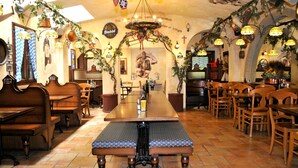 Een restaurant met een lange houten tafel, banken en hangende lampen.