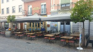 Een terras met tafels en stoelen, een bord met Hotel Vittoria en een gebouw met een balkon.