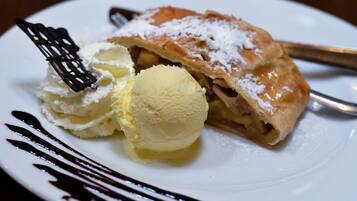 Un plato de postre con un pastel, helado y un chorrito de chocolate.