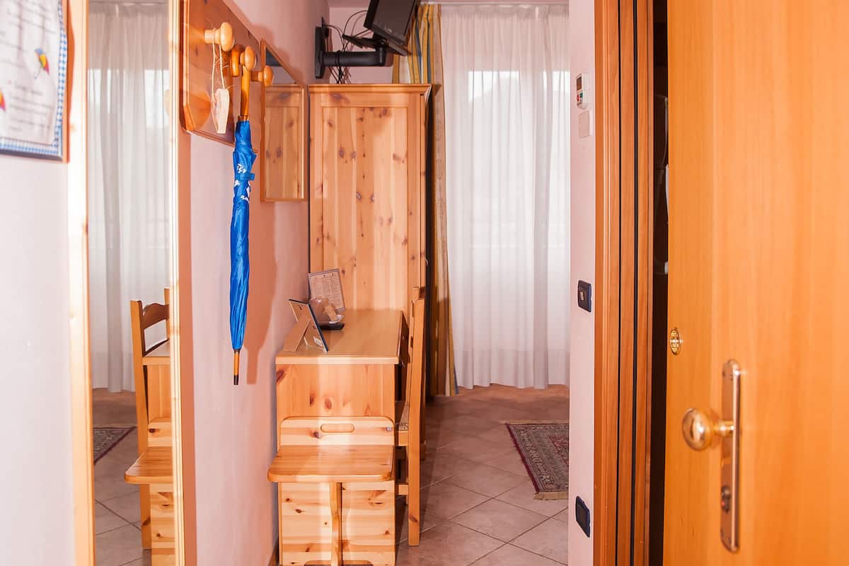 Un corridoio con una scrivania in legno, uno specchio e una porta.