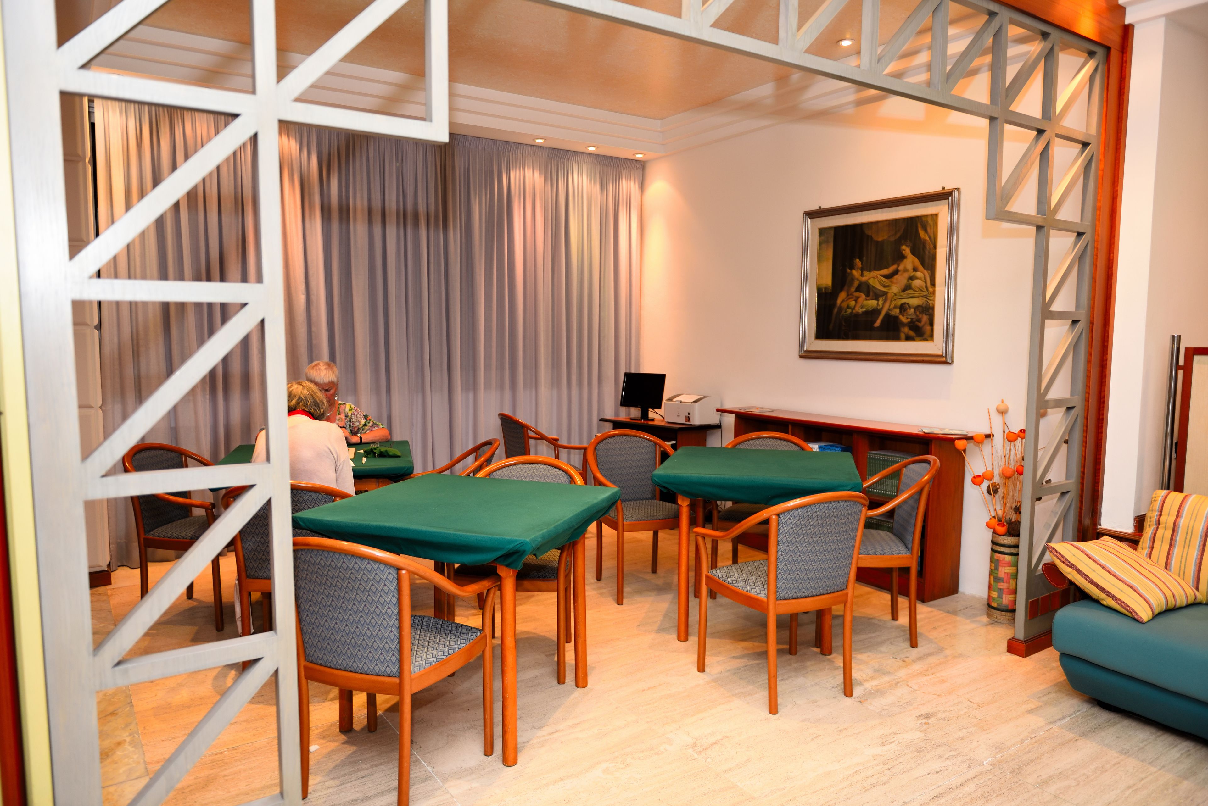 Un espace repas avec des chaises et des tables en bois, un tableau accroché au mur et un escalier.