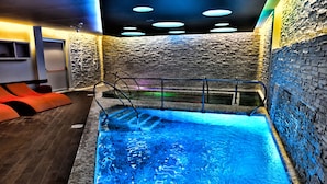 A spa area with a hot tub, stone walls, and orange seating.