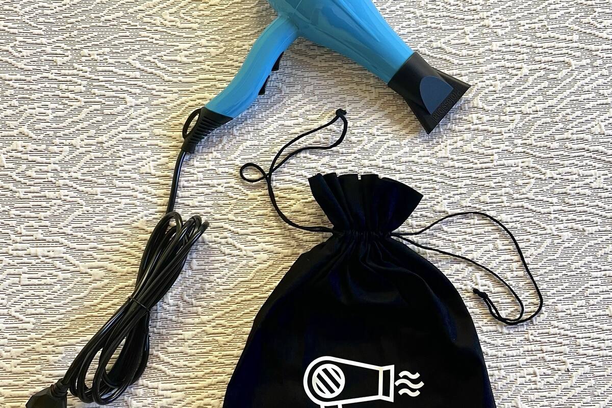 Un sac noir à cordon de serrage orné d’une icône blanche représentant un sèche-cheveux, un sèche-cheveux bleu et un câble de recharge noir.