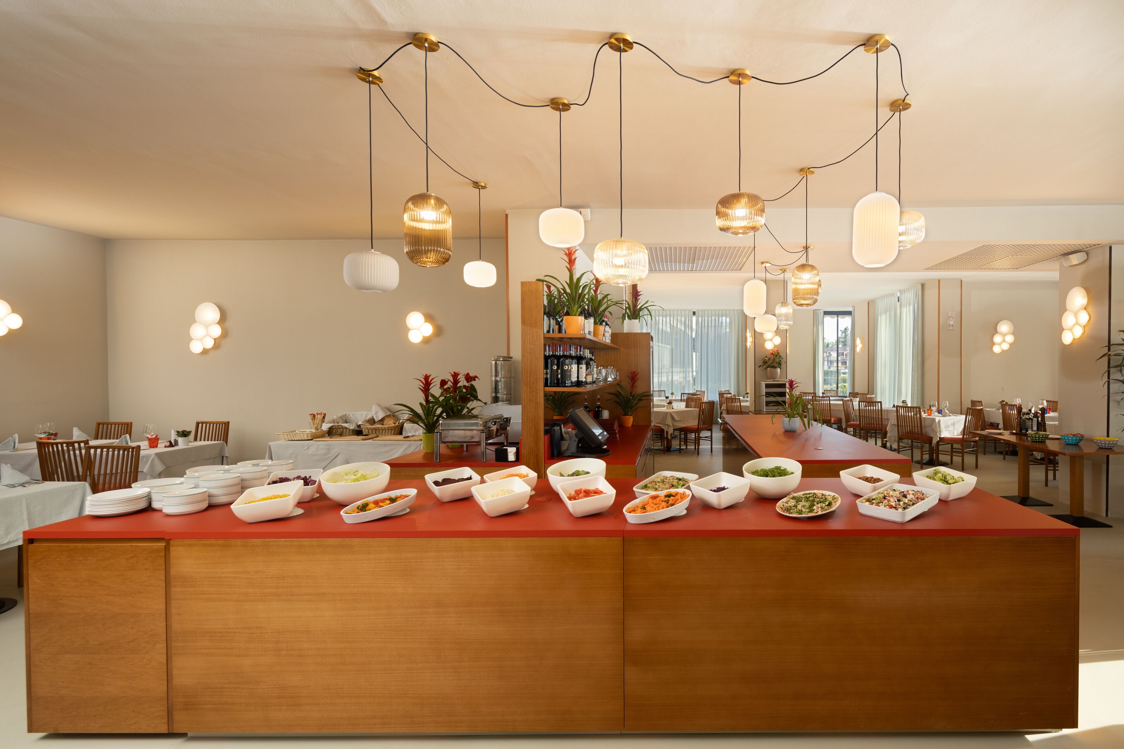A spacious dining area with a long wooden table, multiple dining chairs, and a variety of dishes on a central island.