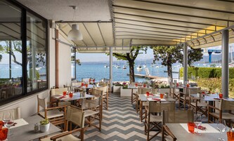 Una terraza con mesas y sillas, con vistas a un puerto deportivo y barcos.