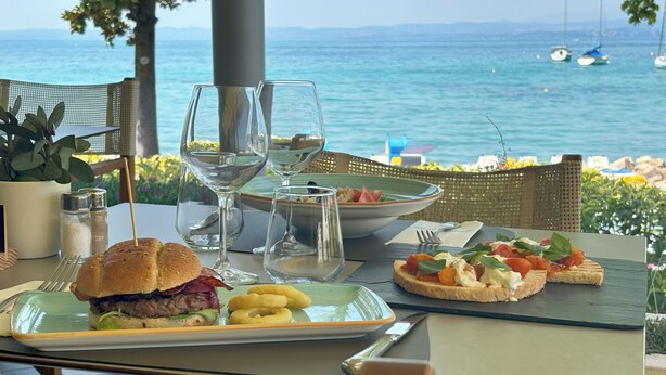 Una mesa con comida, vasos y vistas al mar.
