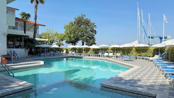 Una piscina al aire libre, sombrillas, sillones reclinables de piscina