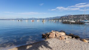 Un puerto deportivo con barcos amarrados, agua tranquila y costa rocosa.