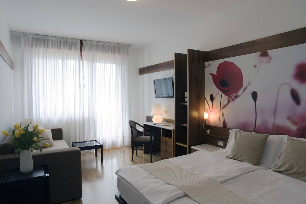 Habitación de hotel con cama, escritorio, silla y televisión.