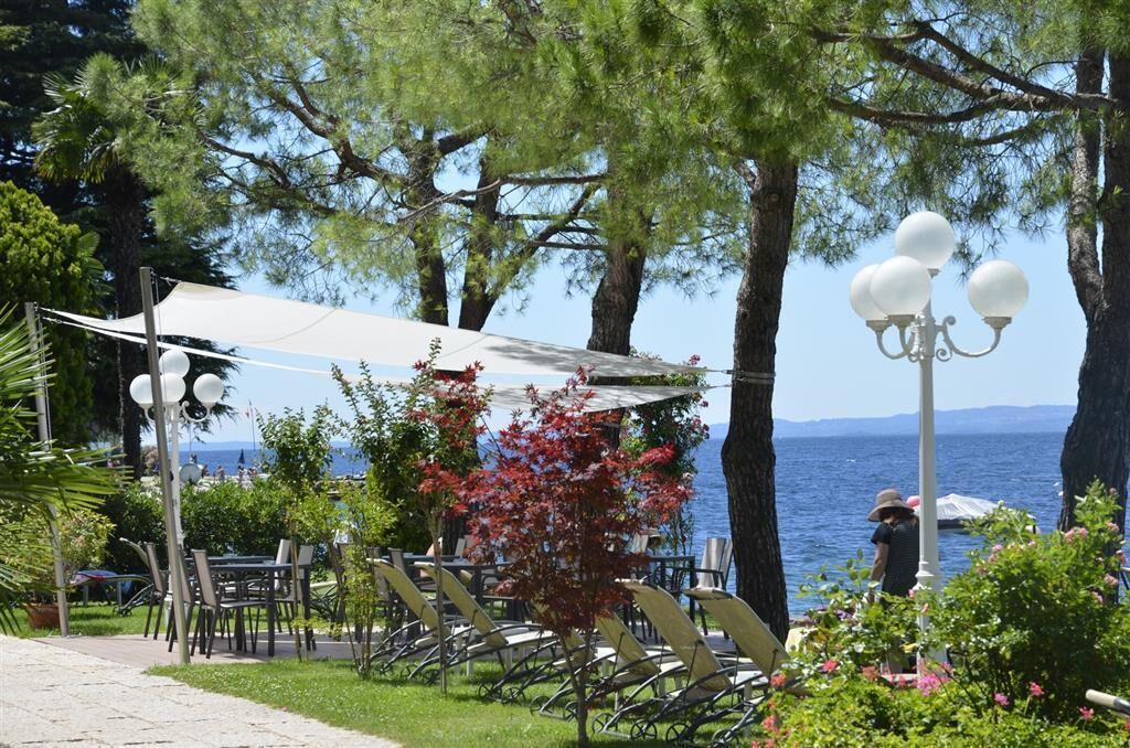 An outdoor seating area with tables and chairs, a canopy, and a view of the sea.