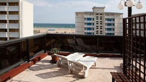 A rooftop terrace with two lounge chairs and a potted plant, overlooking a beach and a hotel building. - Hotel Santa Lucia (San Michele al Tagliamento)