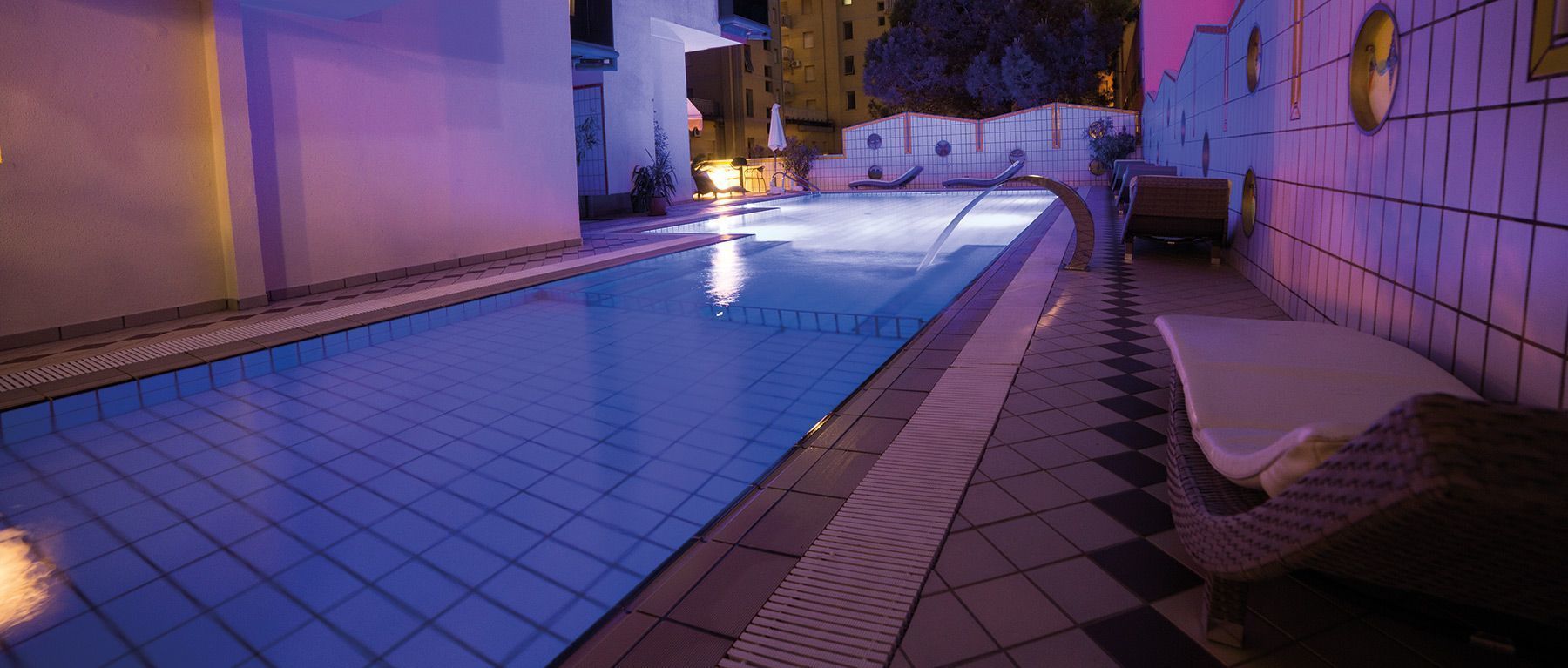 Une piscine dont le fond est recouvert de carrelage et qui est bordée de chaises longues.