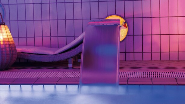 A pool area with a lounge chair and a sunbed, surrounded by tiled walls. - Hotel Santa Lucia (San Michele al Tagliamento)