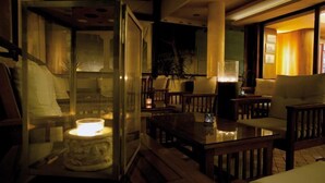 A dimly lit lounge area with wooden furniture and a glass partition. - Hotel Santa Lucia (San Michele al Tagliamento)