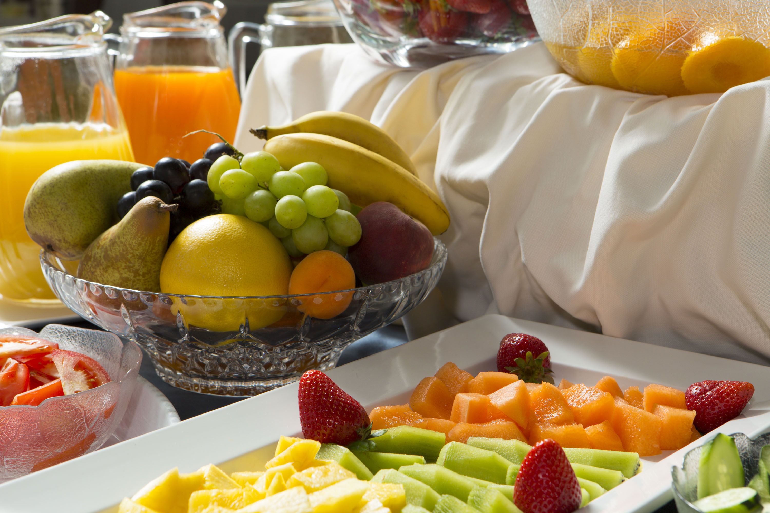 A breakfast buffet with a variety of fruits and a pitcher of orange juice.