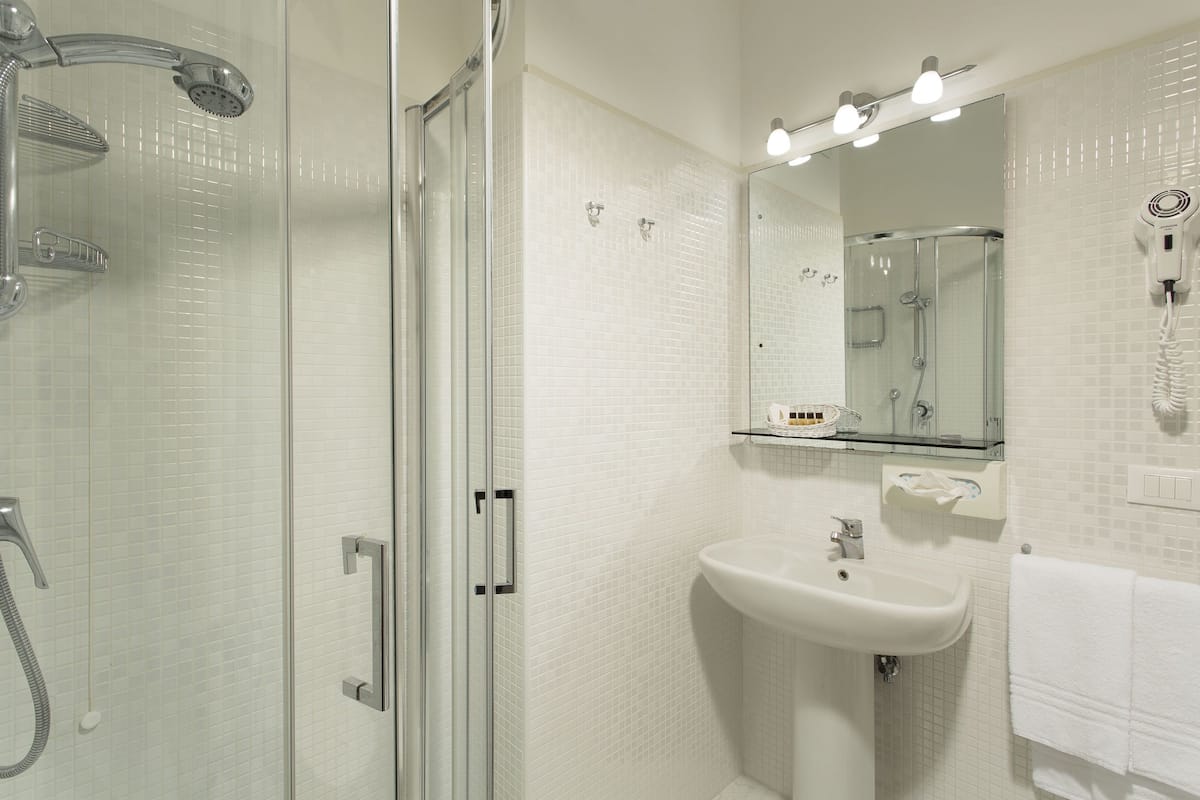 A modern bathroom with a glass-enclosed shower, a white sink, and a mirror above it.
