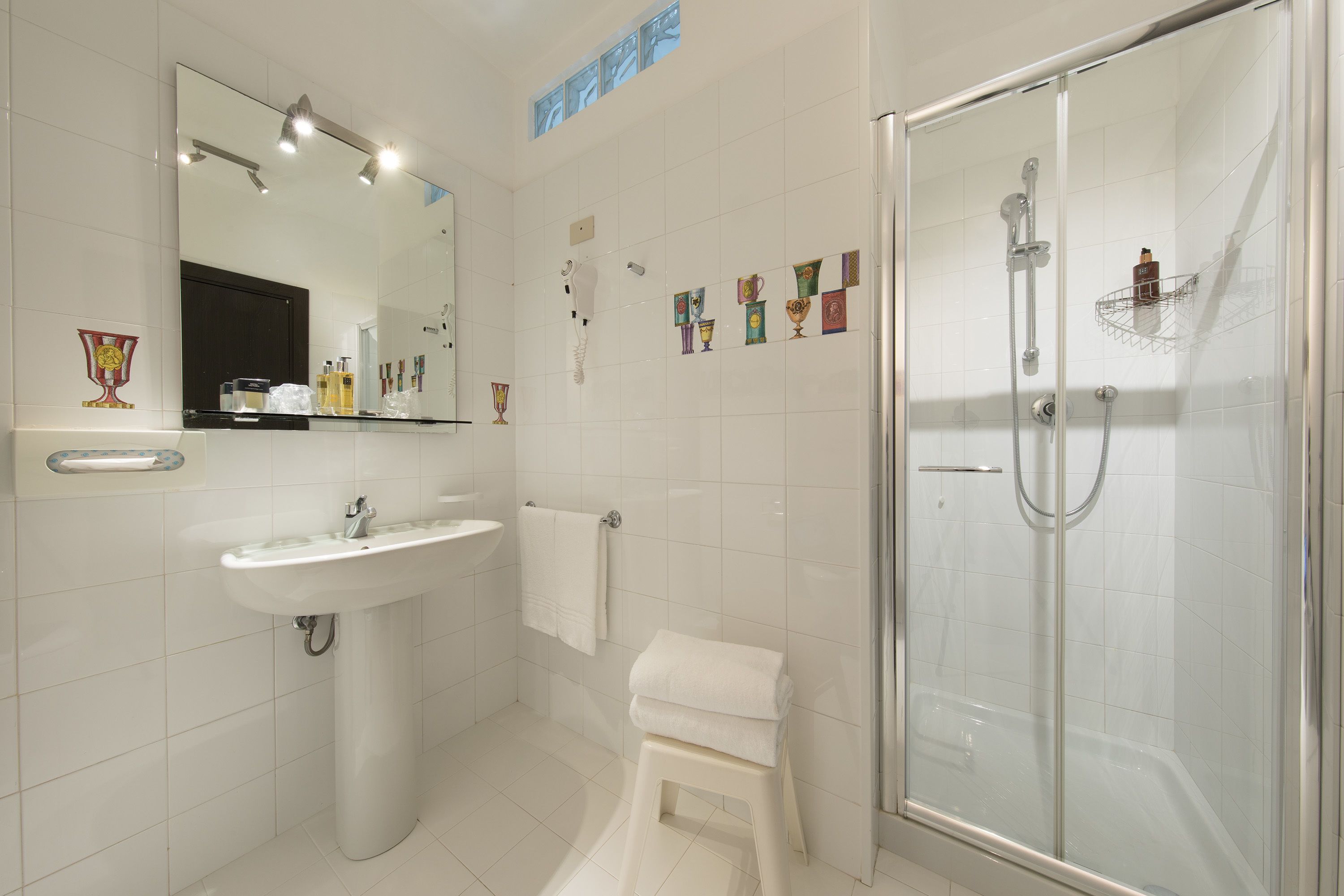 Une salle de bain moderne avec une douche à parois de verre, un lavabo blanc et un miroir au-dessus.