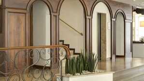A grand staircase with ornate railings, leading to a landing with a decorative planter. - Hotel Byron Bellavista (Jesolo)