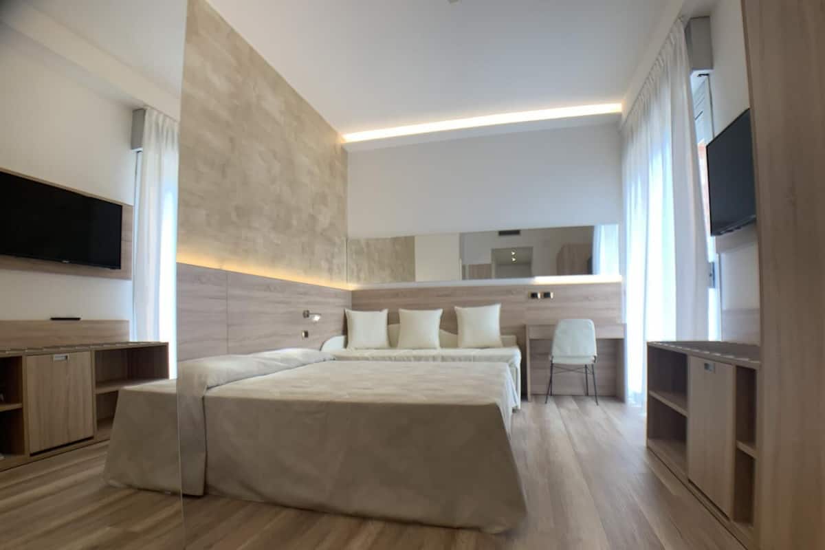 A modern bedroom with a large bed, a desk, and a TV.