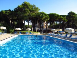 Una piscina al aire libre, sombrillas, sillones reclinables de piscina