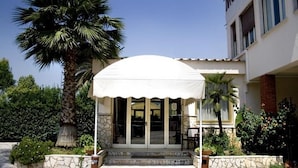 A building with a covered entrance, stone steps, and a palm tree. - Hotel Salaria (Rome)