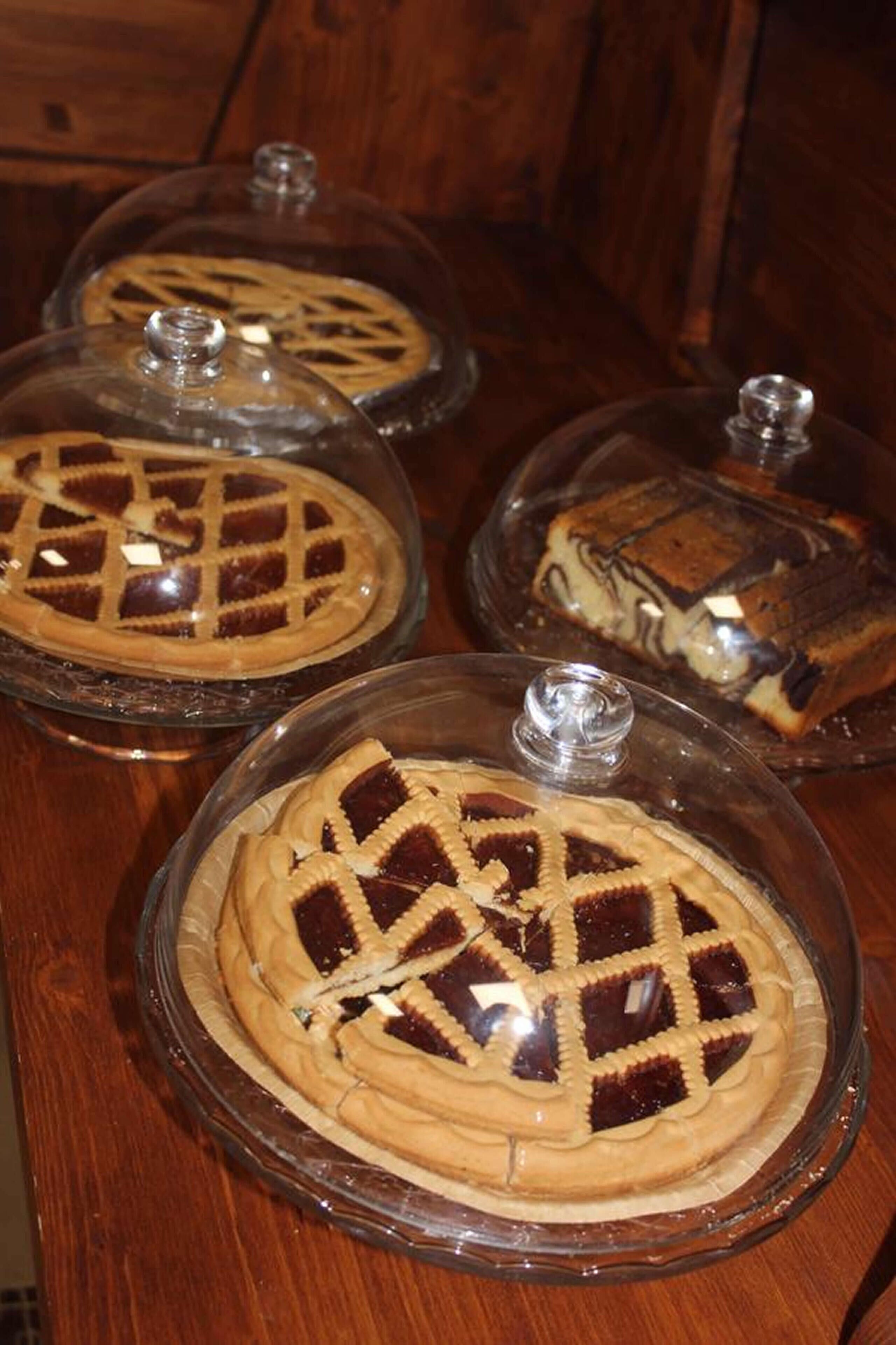 Tre torte coperte da cupole di vetro su un piano di legno.
