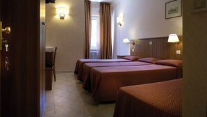 A hotel room with three beds, a wooden headboard, a small table, and two wall-mounted lamps. - Hotel Salaria (Rome)