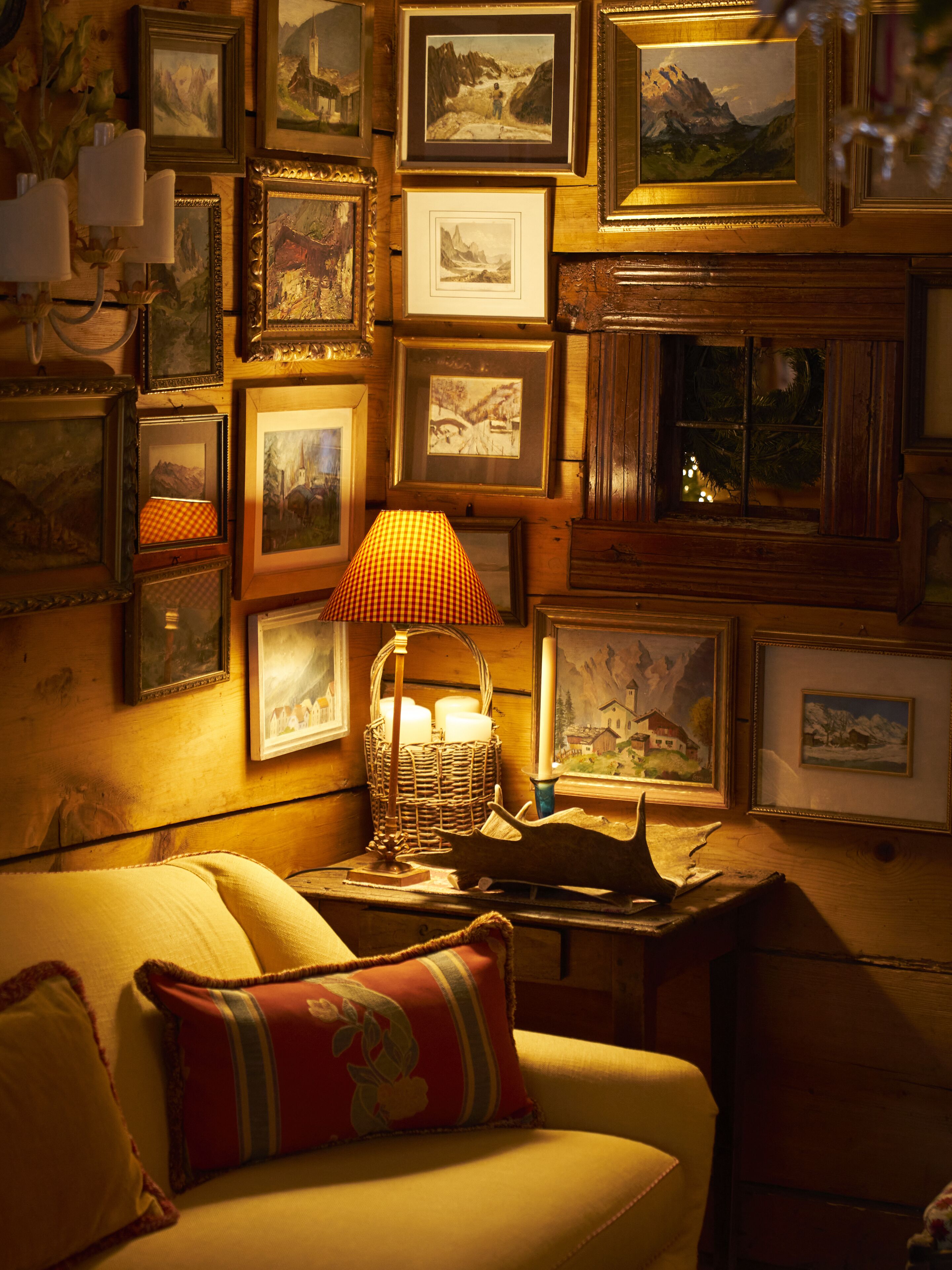 Ein gemütliches Zimmer mit einer Couch, einer Lampe und einer Wand mit gerahmten Bildern.