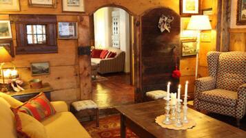 Un salon chaleureux avec un plancher en bois, un canapé jaune, un fauteuil à motifs et une table basse décorée de bougies.