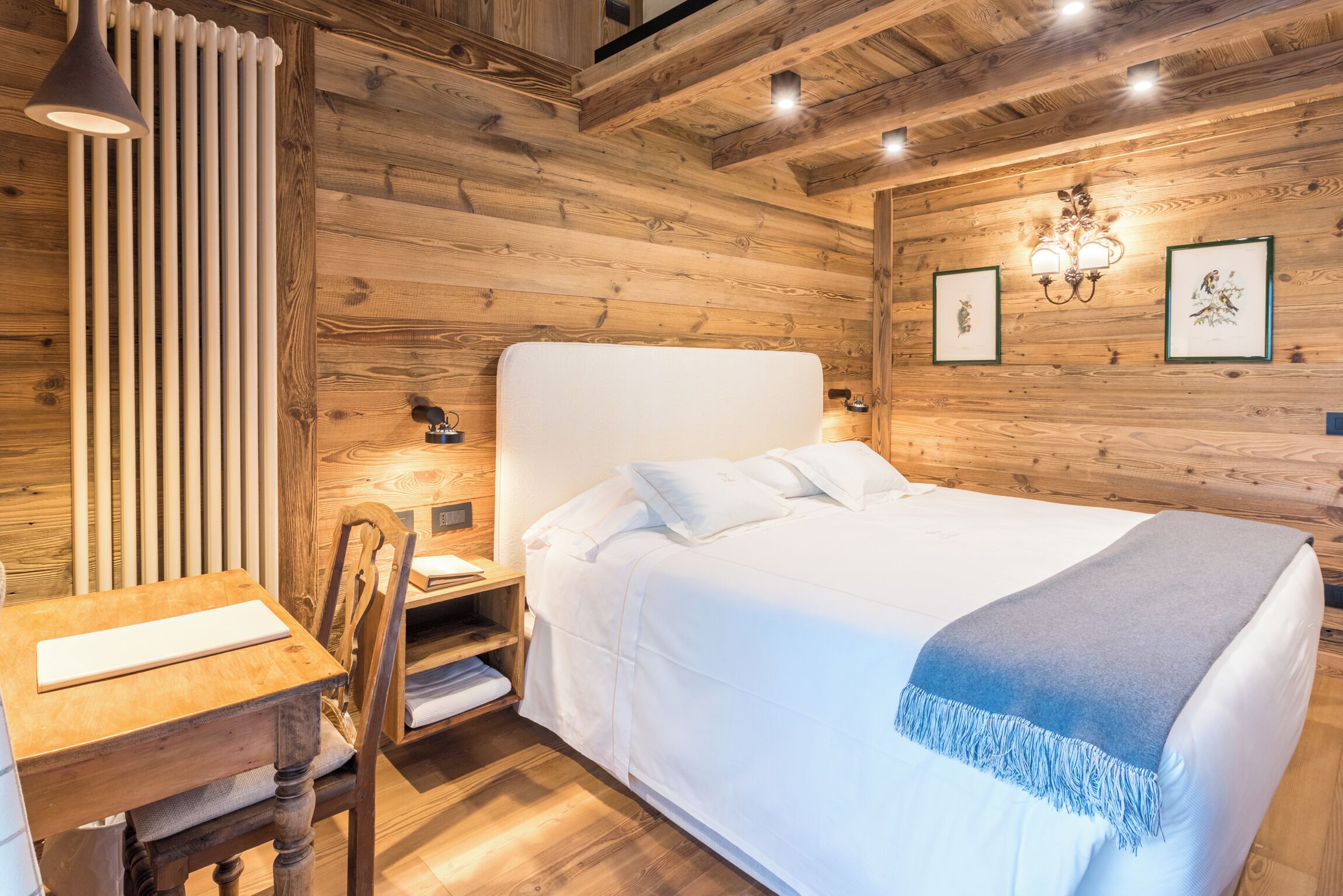 A wooden-paneled room with a bed, a desk, and a chair.