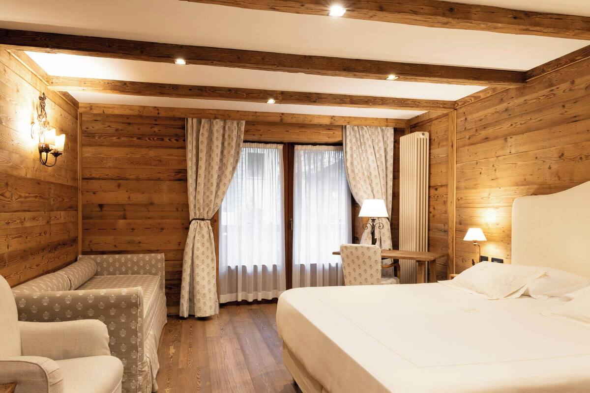 Una habitación acogedora de madera con una cama, una silla, una mesa y una lámpara.