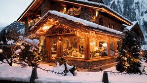 A cozy log cabin with a stone facade, large windows, and a snow-covered roof. - Auberge de La Maison (Courmayeur)