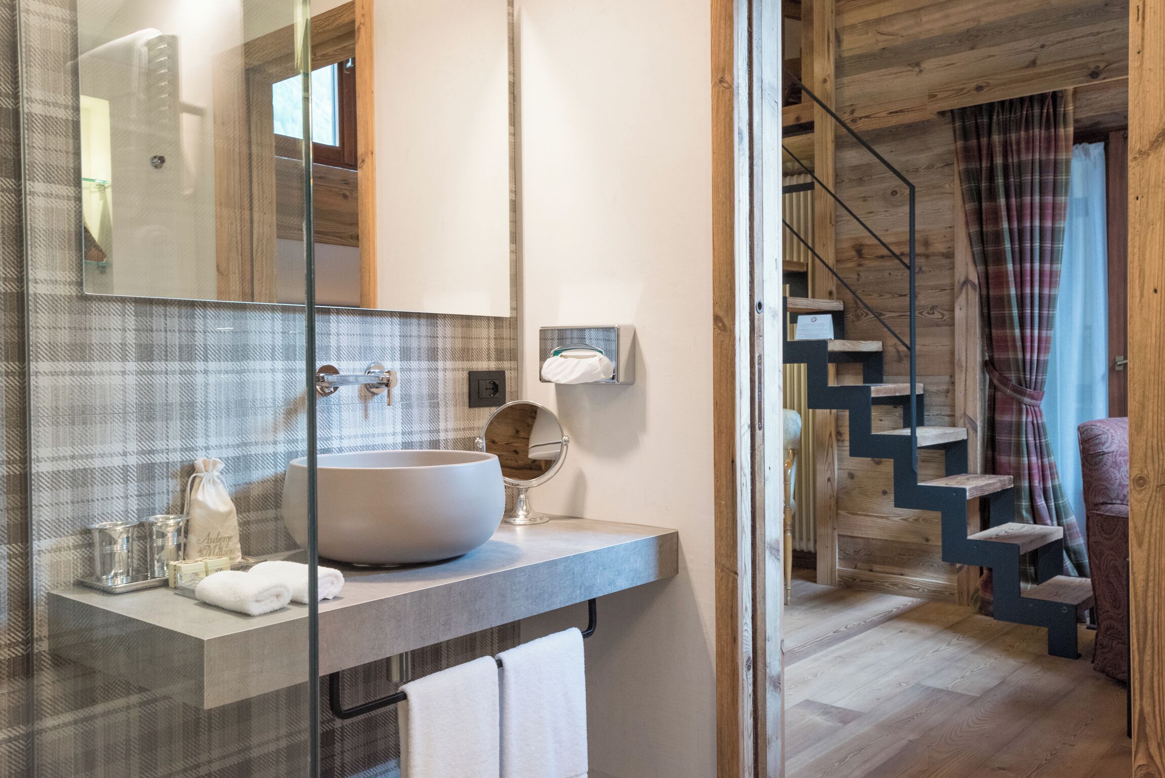 A modern bathroom with a large vessel sink, a mirror, and a towel rack.