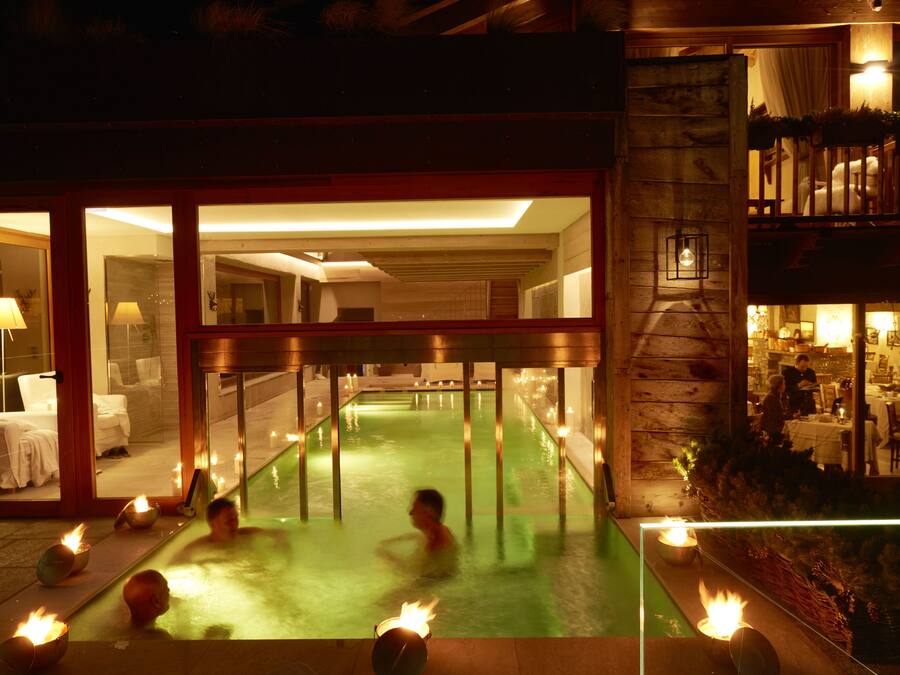 A pool area with multiple people, indoor lighting, and a visible restaurant or dining area.