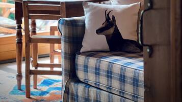 A cozy seating area with a checkered sofa and a wooden table set for dining, featuring a wine glass and a bottle.