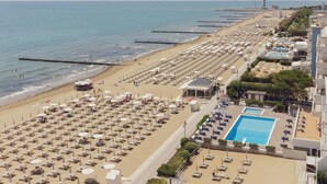 A beach resort with rows of sunbeds and umbrellas, a swimming pool, and a pier extending into the sea. - Hotel delle Nazioni (Jesolo)