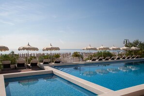 A swimming pool with lounge chairs and umbrellas, overlooking a coastal view. - Hotel delle Nazioni (Jesolo)
