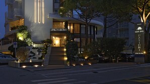 A modern hotel with a prominent vertical light design on the facade, a staircase leading to the entrance, and a well-lit entrance area. - Hotel delle Nazioni (Jesolo)