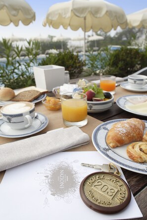 A breakfast table with croissants, coffee, fruit, and juice. - Hotel delle Nazioni (Jesolo)
